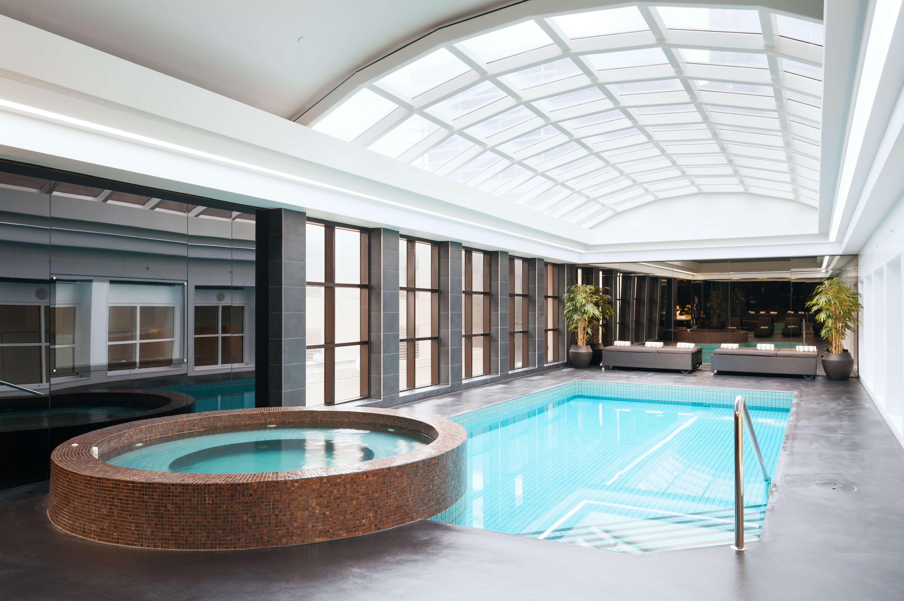 Stamford Plaza Melbourne Hotel Exterior foto The photo shows an indoor swimming pool area. The pool is rectangular and has clear blue water, surrounded by a sleek, modern design. On one side, there is a round hot tub made of dark stone. Large windows line the walls, allowing natural light to fi