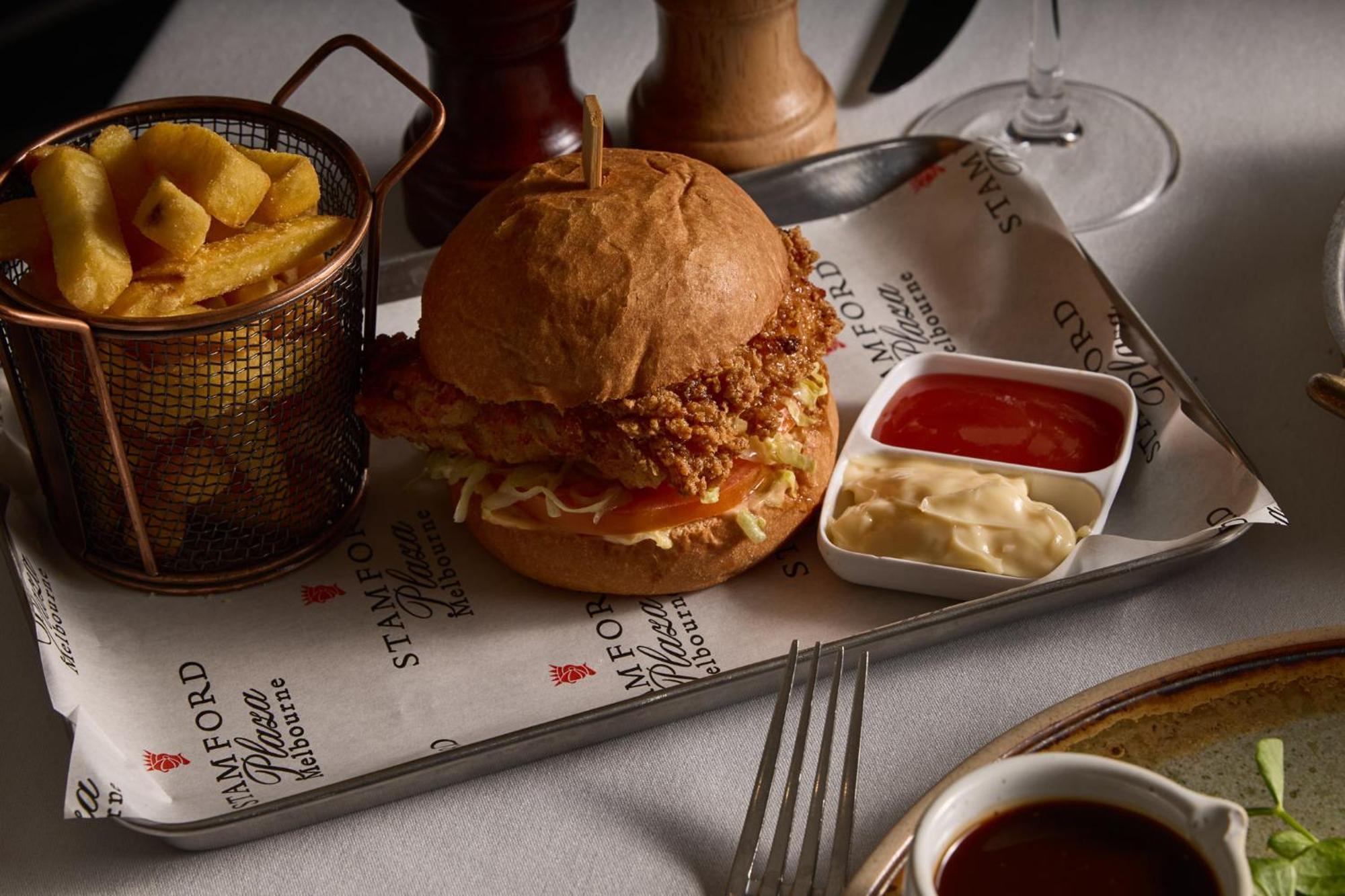 Stamford Plaza Melbourne Hotel Exterior foto The photo features a meal served on a tray. In the center is a sandwich made with a golden-brown chicken fillet that appears crispy, placed inside a soft bun. The sandwich is likely complemented by some type of sauce or condiments underneath the chic