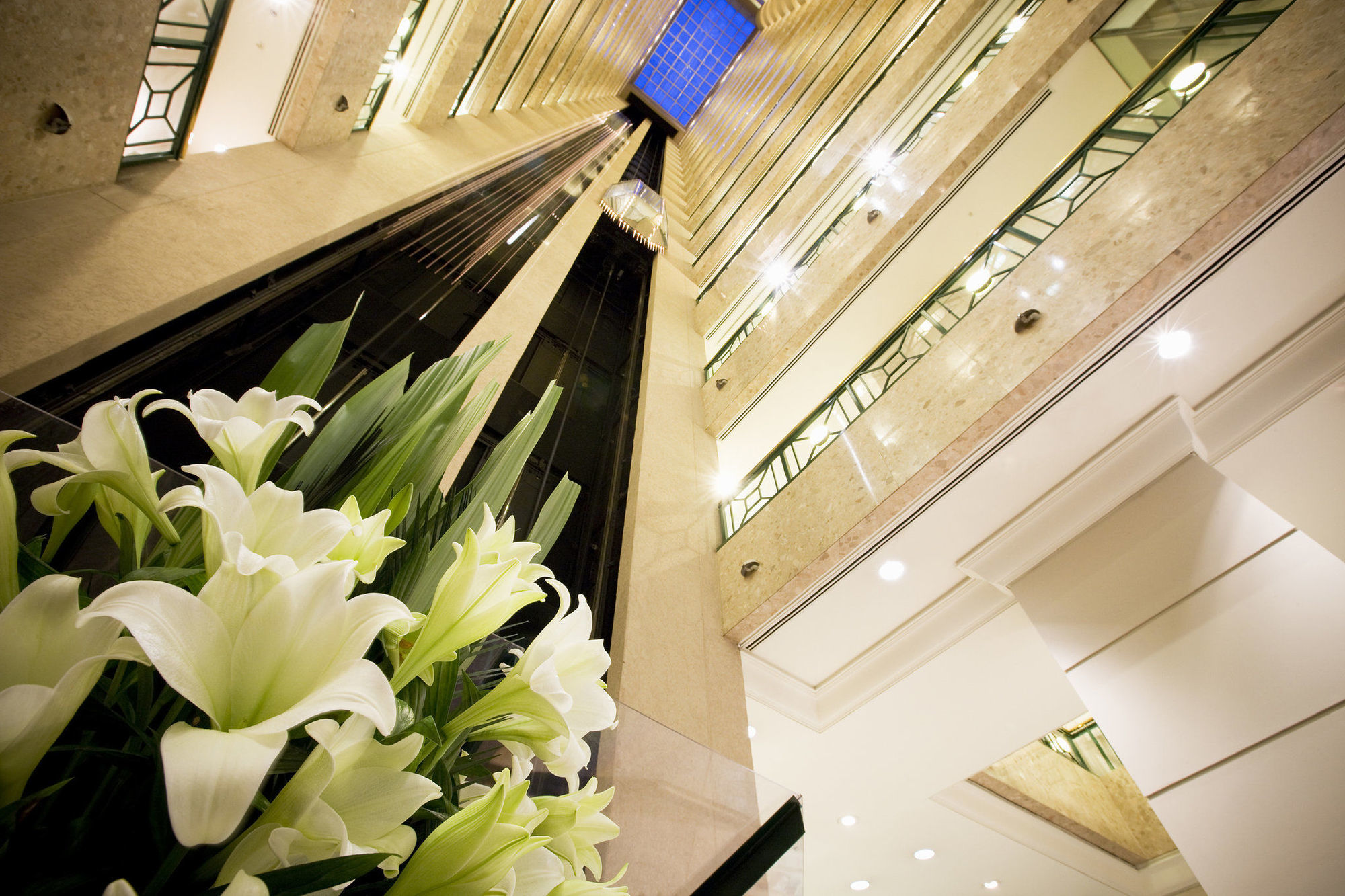 Stamford Plaza Melbourne Hotel Interior foto The photo shows a modern indoor space, likely a lobby or atrium of a building. The view is looking upwards, capturing a sleek design with multiple levels. There are several elevators in the center, running vertically. The walls are lined with glass a